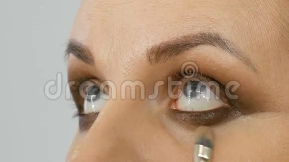 专业主妆师将米色眼影在美容院闭眼处用特殊刷子刷上模型眼视频的预览图