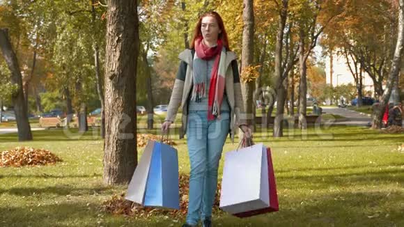 一个长着狐假虎威的女孩穿着五颜六色的纸袋穿过公园视频的预览图