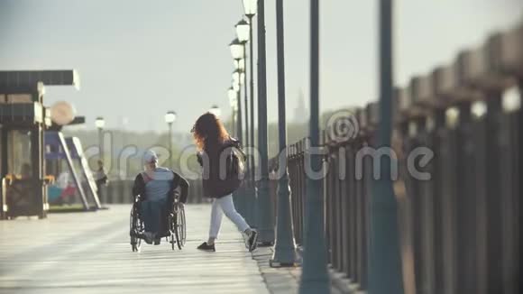 坐轮椅的残疾人在码头给年轻女子拍照视频的预览图