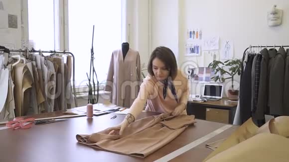 年轻女子的肖像她正在她的工作室里包装棕色的衣服视频的预览图