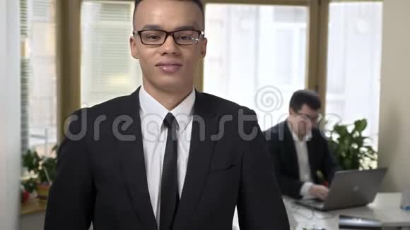 年轻成功的非洲商人看着相机并显示了一个类似的标志在电脑里工作的人视频的预览图