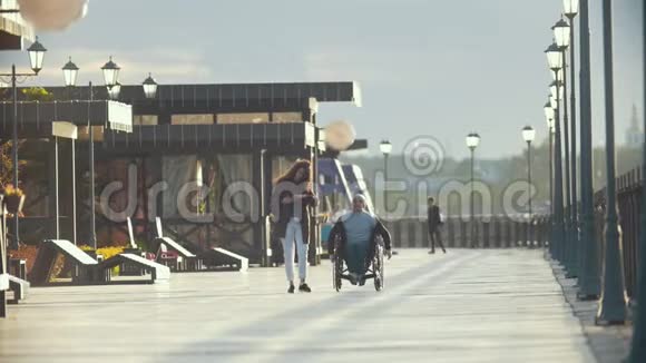 坐轮椅的残疾人在码头为年轻女子拍照视频的预览图
