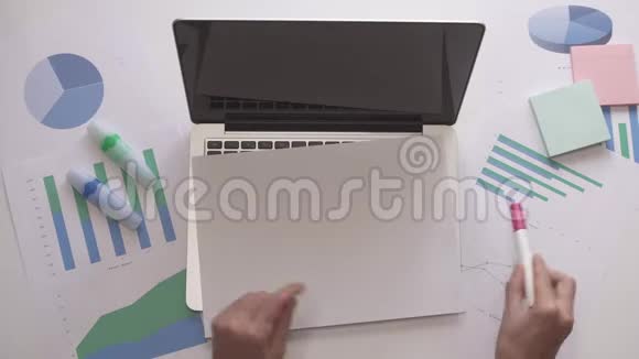 女人在笔记本电脑上用一张纸写在线作业带有图表的办公桌面视频的预览图