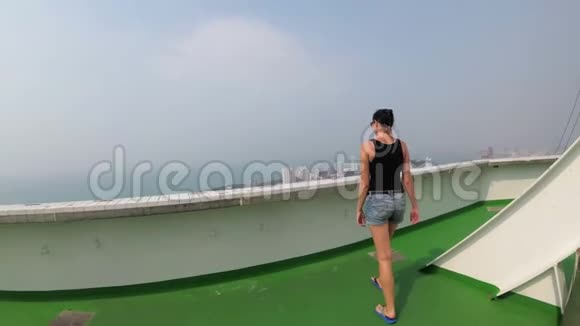一位妇女沿着摩天大楼屋顶的边缘行走视频的预览图