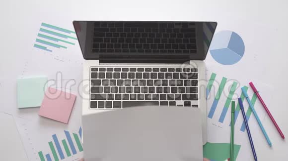 女人在笔记本电脑上的一张纸上写SEMINAR带有图表的办公桌面视频的预览图