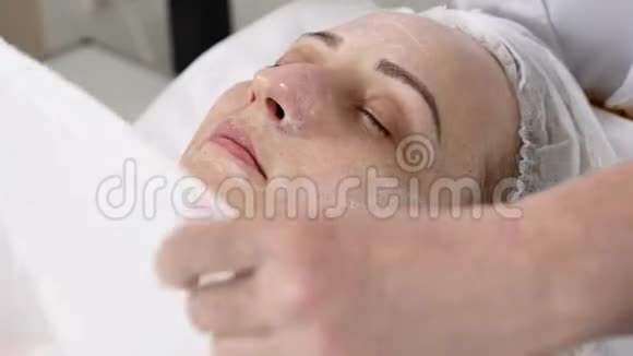 美容诊所年轻女人有专业的面部手术美容师用毛巾温暖女性客户的脸视频的预览图