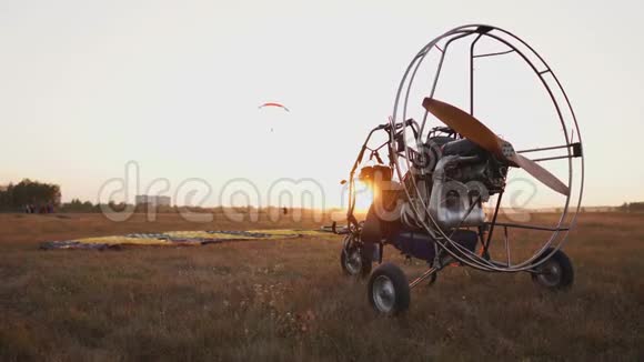 汽车滑翔伞站在机场在夕阳的阳光下在背景下一个跳伞者降落视频的预览图