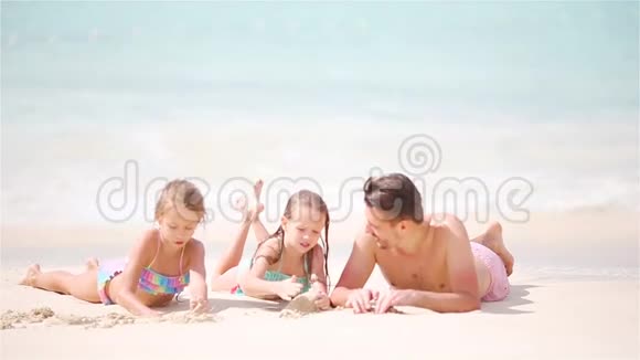 一家人在白色海滩上玩得很开心孩子们和爸爸躺在浅水里视频的预览图