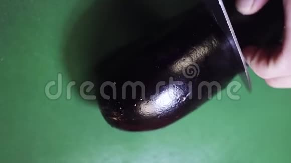 绿色餐桌上用锋利的大刀切割茄子的俯视图视频的预览图