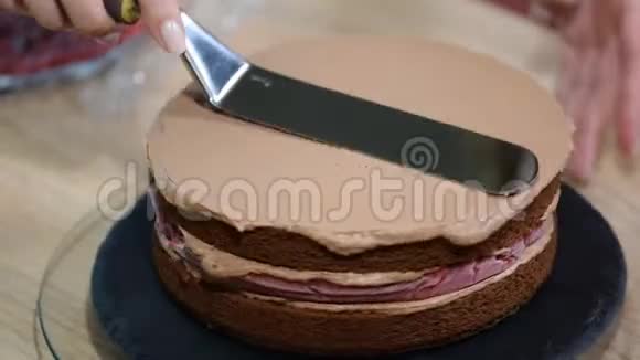 厨师做巧克力奶油厨师把蛋糕层贴在奶油上烹饪分层蛋糕做分层饼视频的预览图