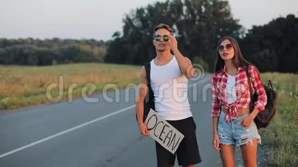 一对年轻夫妇正站在路上搭便车一男一女在高速公路上停着车车上挂着海洋号视频的预览图