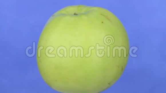 一个绿色成熟的苹果在蓝色上分离视频的预览图