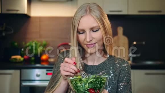 很高兴女人吃健康沙拉美丽的年轻女性享受健康的蔬菜沙拉同时看着相机视频的预览图