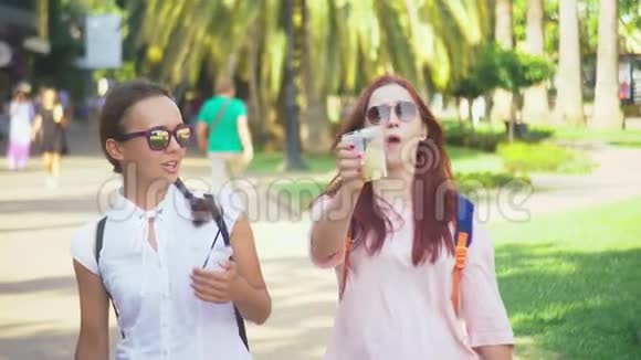 两个女孩在外面散步时交谈和喝鸡尾酒4K慢镜头拍摄视频的预览图