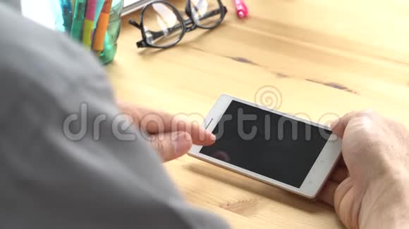商务人员灰色衬衫滑动缩放触摸智能手机家庭办公室水平视频的预览图