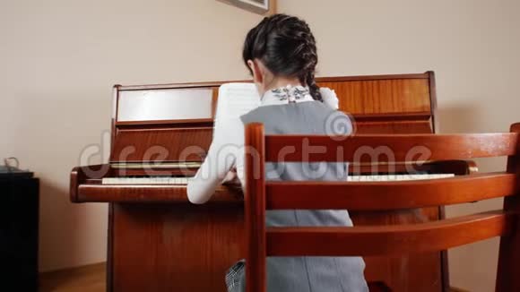音乐课弹钢琴的女孩从孩子的背部看游戏的滑动视图视频的预览图