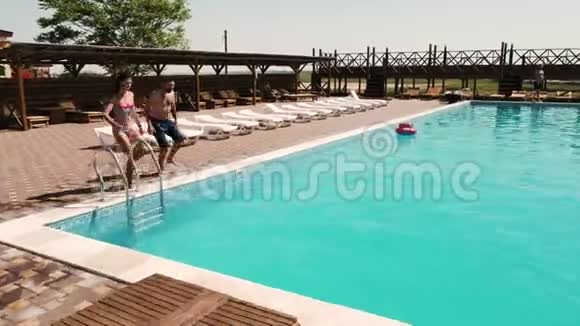 一对欢快的情侣跑着跳进游泳池视频的预览图