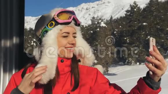 滑雪场女人在机舱滑雪电梯的智能手机上自拍视频的预览图