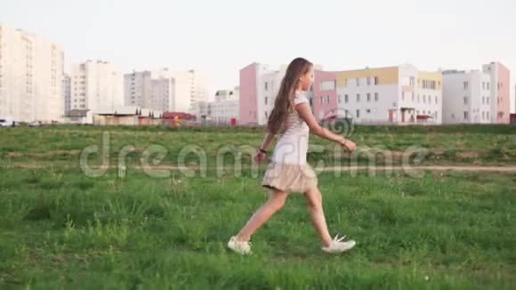 可爱的小女孩在城市荒地的草地上散步视频的预览图