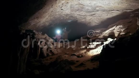 三个戴着头盔的少年用灯笼检查黑暗的洞穴视频的预览图