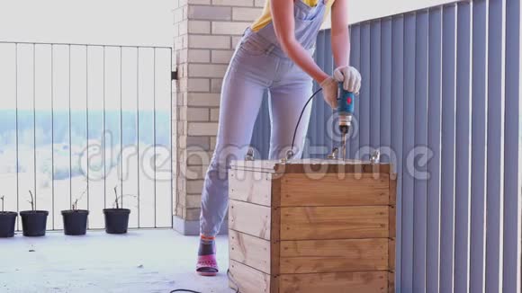 一个女人在露台上做一项非女人的工作用螺丝刀在木箱里钻一个洞视频的预览图