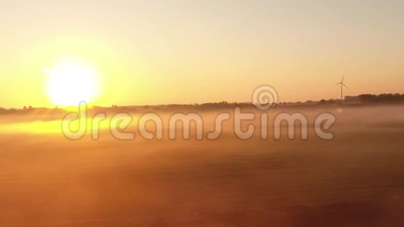 用日出和风力涡轮机飞越多云的田野视频的预览图
