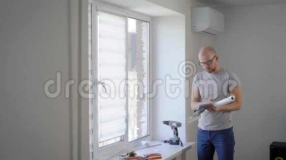 年轻人正在安排一些细节在白天卧室的窗户上安装白色防护窗帘视频的预览图