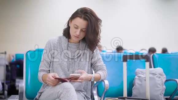 女子正在机场候机厅检查护照和机票上的数据并在网上登记视频的预览图