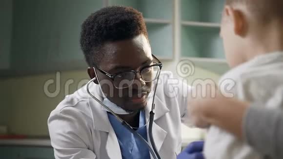 年轻的非洲儿科医生在医院办公室用听诊器检查小男性病人视频的预览图