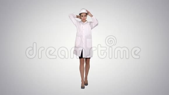 女工程师穿着白色长袍戴着白色安全帽走在渐变的背景上视频的预览图