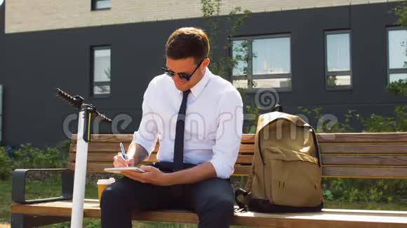 商人坐在长凳上写着笔记本视频的预览图