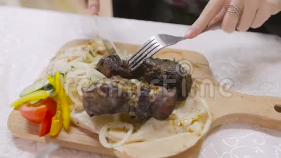 在切一块蔬菜烤肉的同时用刀叉将女性的手收起来视频的预览图