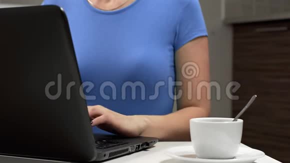 女人在工作场所用笔记本电脑工作喝咖啡在办公室工作用笔记本电脑打字喝咖啡视频的预览图