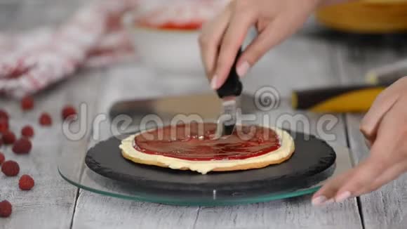 女性糕点厨师用旋转蛋糕架制作美味的分层蛋糕鲜奶油和浆果果酱视频的预览图