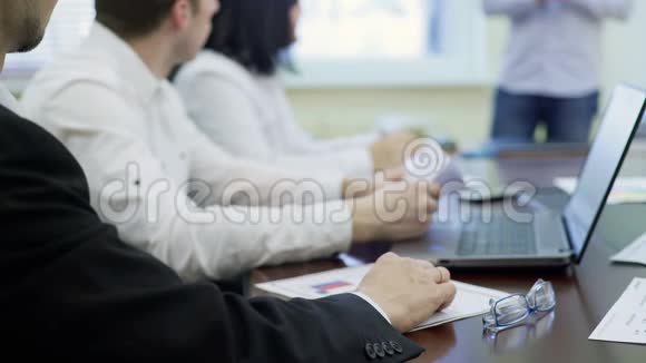 公司员工在商务会议上坐在桌旁听着领导讲话视频的预览图