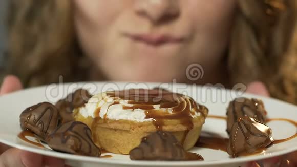 女孩舔嘴唇的糖果巧克力下的焦糖上的盘子特写视频的预览图