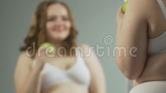 年轻女子吃苹果对内衣的身体反射很满意视频的预览图