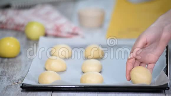 烘焙前的酵母包子用烤纸躺在烤片上烹饪过程视频的预览图