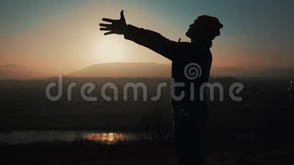 日落时分人类的剪影举起双手站在山上自由概念视频的预览图