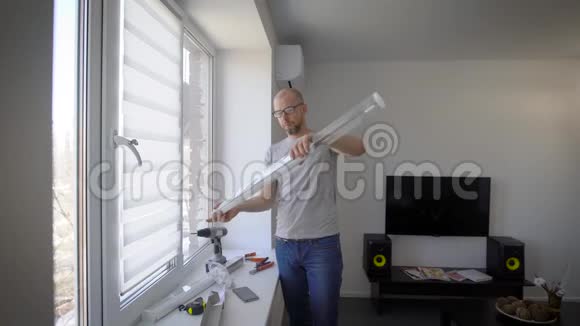 师父白天在一间灯光室里安装白色塑料窗百叶窗在画布上测量和尝试视频的预览图