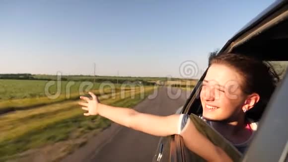 美丽的女孩坐在车里双手放在窗前微笑着在明亮的灯光下挥动着她的手视频的预览图