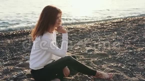 年轻的女人静静地坐在海滩上视频的预览图