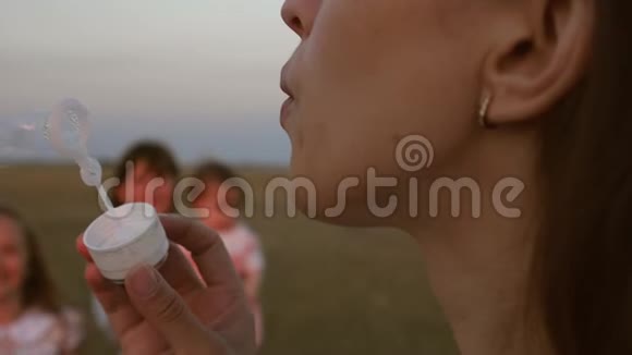 快乐的妈妈和孩子们一起吹肥皂泡夏天孩子们在公园里捉泡泡笑慢慢视频的预览图