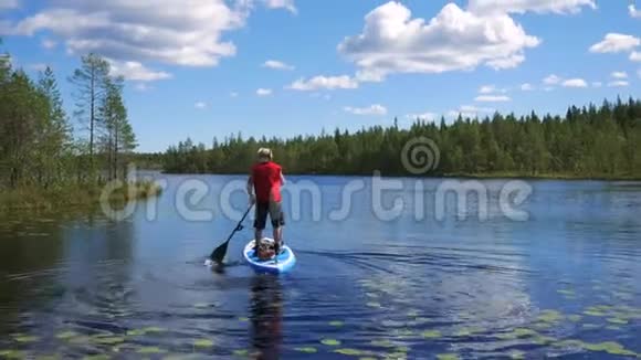 男人在湖上漂浮在一艘充气船上站在她身上用手划桨视频的预览图
