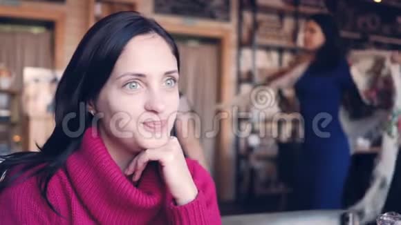 一个年轻的女人坐在咖啡馆的桌子旁边喝咖啡边说话视频的预览图