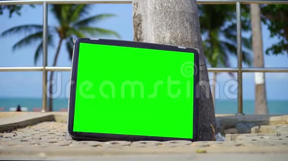 电视站在海滩上带有绿色屏幕的电视你可以用你想要的镜头或图片替换绿色屏幕视频的预览图