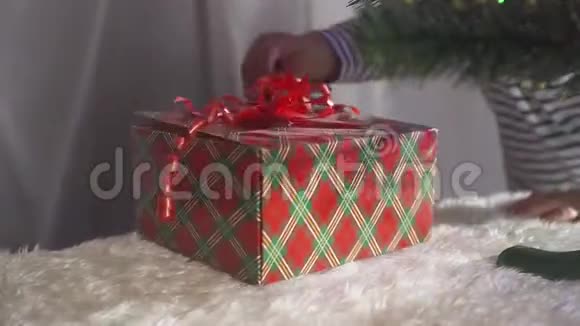 两岁的小男孩得到了一份礼物礼物上有一根红丝带还有一棵圣诞树还有很多礼物盒视频的预览图