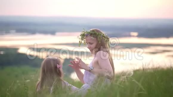 快乐的母女在夏天的日落时分在山上休息视频的预览图