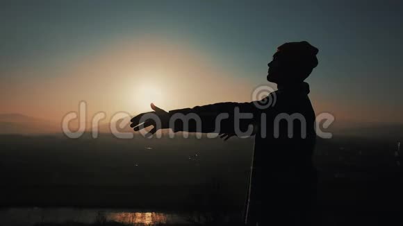 日落时分人类的剪影举起双手站在山上自由概念视频的预览图
