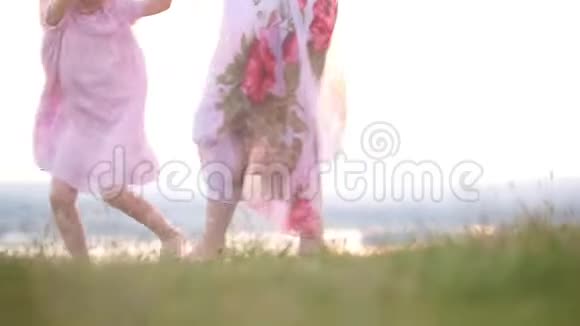 在夏天的日落时分母亲和女儿赤着脚在草地上嬉戏视频的预览图